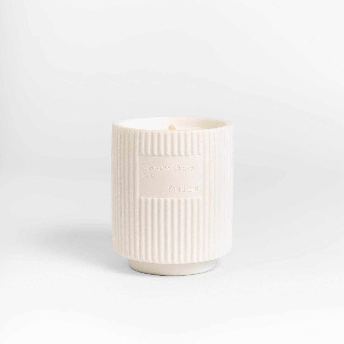 White textured candle in handmade ceramic vessel on a light gray background