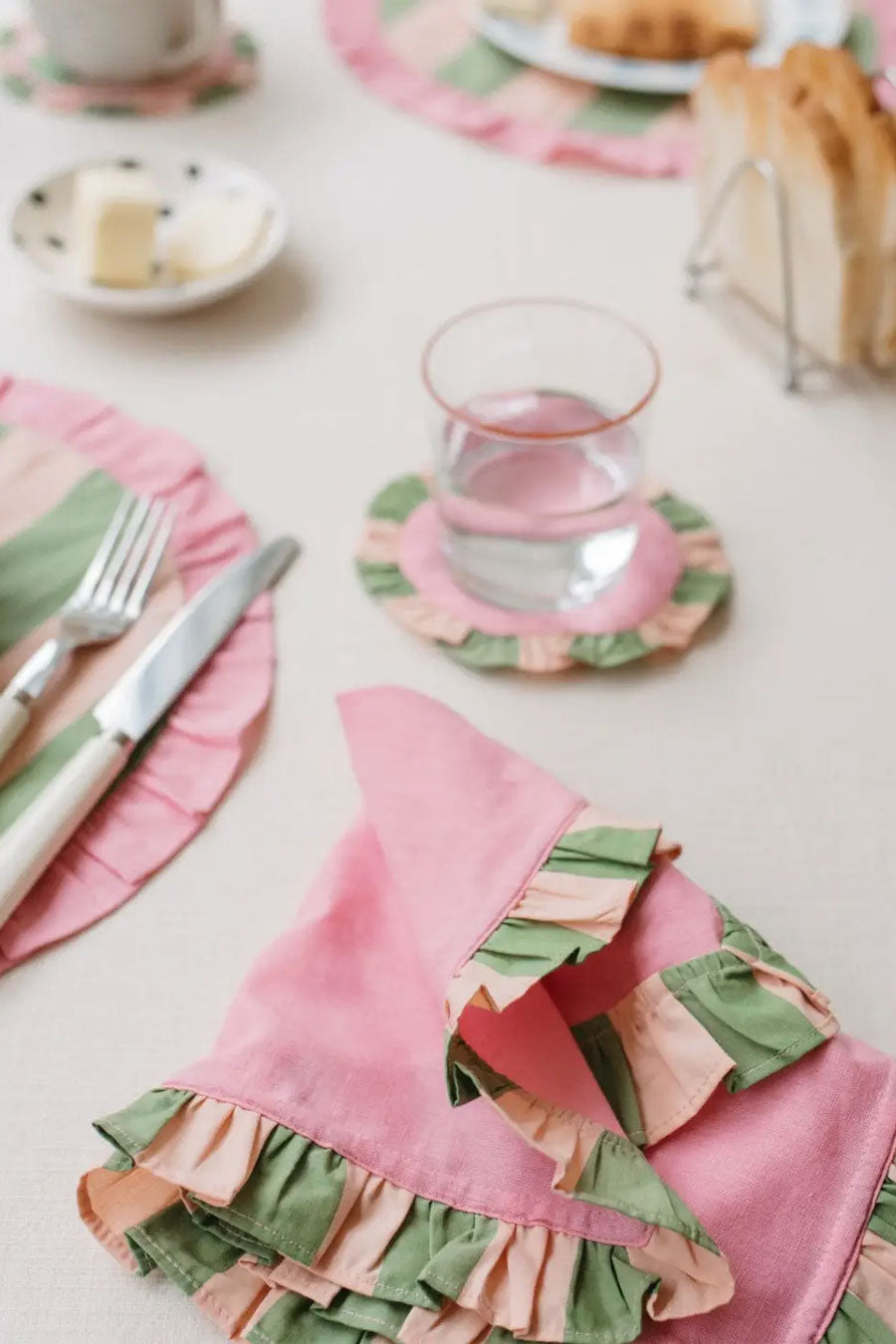 white table with pink cloth napkins and green striped coasters