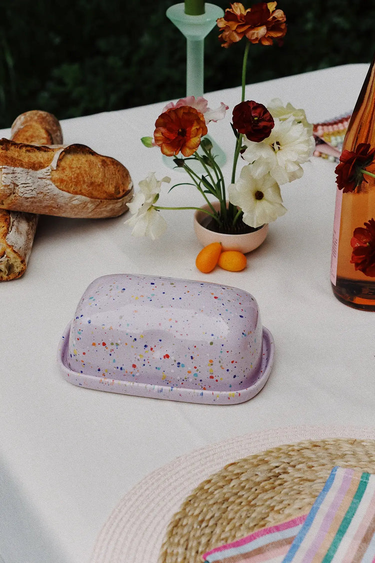 table with kitchen decor: lilac butter dish, placemats & vase