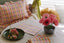 archive new york orange and pink artisan napkins and ruffle pillow at dining nook table