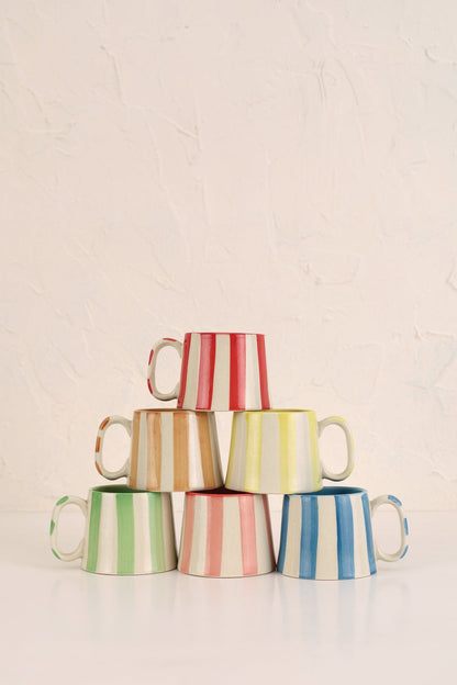 Stack of colorful striped mugs on a light background
