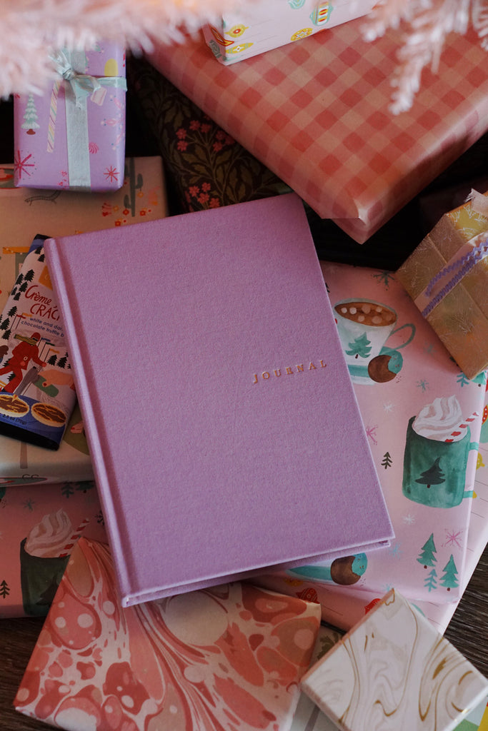 wallflower holiday gift guide - lilac linen journal with pink christmas presents under tree
