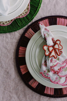 red and pink place setting with woven placemats and napkin rings from wallflower