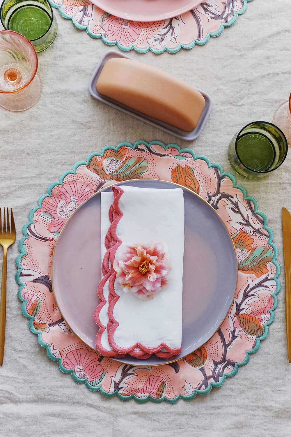 floral place settings with round scalloped placemats and ceramic butter dish
