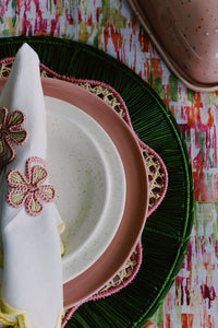 pink and green round woven placemat and palm flower napkin rings for spring place setting by wallflower