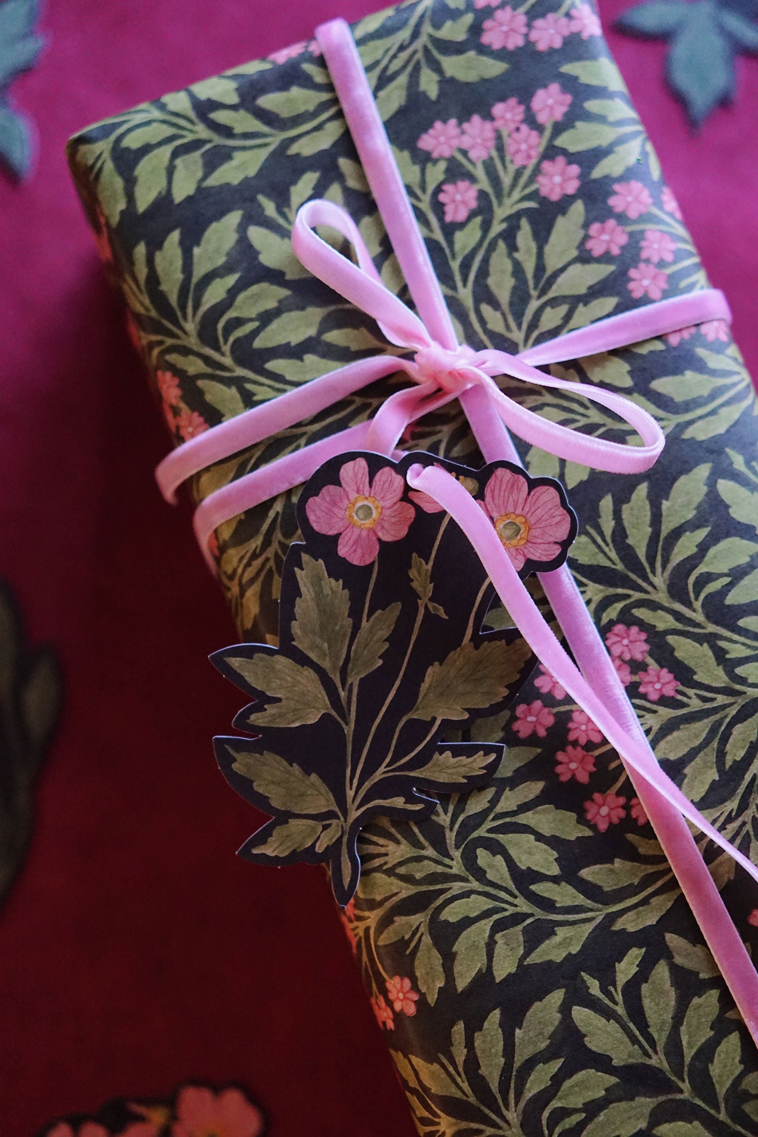 Gift wrapped in floral wrapping paper with a pink ribbon on a red background