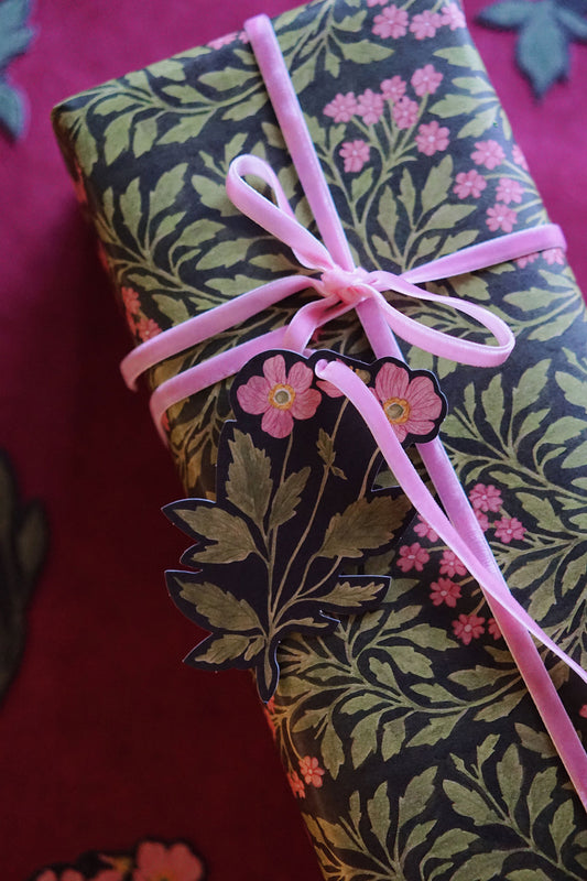 Gift wrapped in floral wrapping paper with a pink ribbon on a red background
