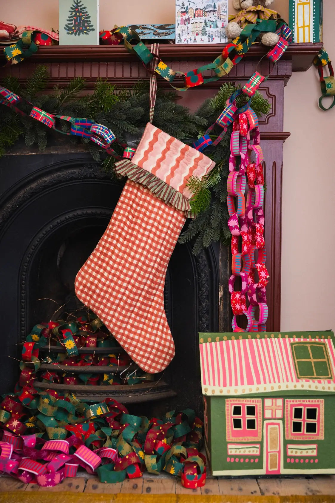 gingham red and pink block printed handmade quilted christmas stockings on maximalist mantel with paper chains ✿ shop christmas stockings at wallflower